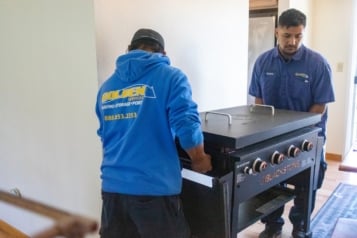 Mover in blue Golden Services LLC uniform preparing a large item for transport