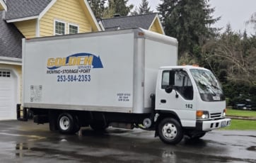 Golden Services yellow box truck parked in a residential driveway